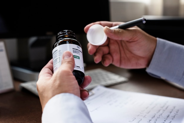A close-up shot of a prescription bottle with a reduced price tag, symbolizing efforts to lower drug costs. A doctor's hand is visible in the background, handing the prescription to a patient.